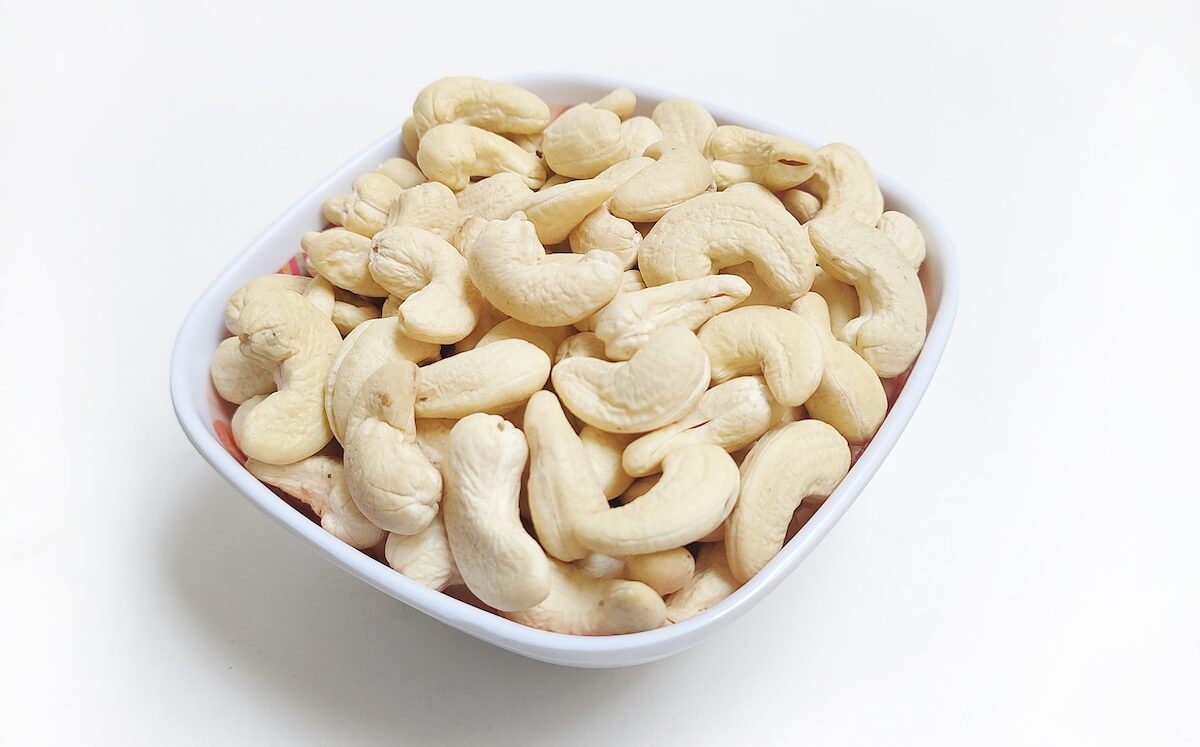 a white bowl filled with cashews on a white surface